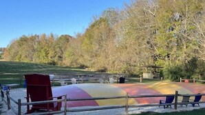 A playground with a colorful slide and seating area, surrounded by trees and a gravel path. - Cherry Treesort "Chico's Hideaway" (Rowan County)