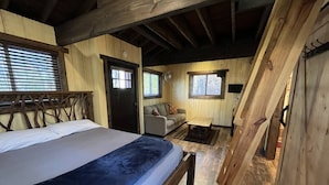 A wooden cabin with a bed, a sofa, and a small table. - Cherry Treesort "Sweet Ashley" (Rowan County)