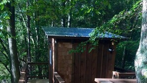 A wooden deck with benches and a small wooden structure in a forested area. - Cherry Treesort "Big Nick" (Rowan County)