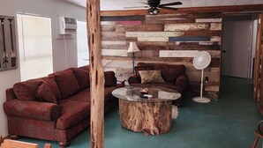 A cozy living room with a wooden ceiling, a round coffee table, a red sofa, and a wooden wall panel.