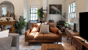 A living room with a brown sofa, a coffee table, a TV, and a bookshelf.