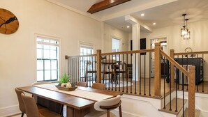 A dining area with a wooden table, chairs, and a clock on the wall.