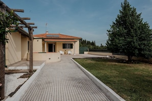 A house with a tiled roof, a paved driveway, and a grassy yard.