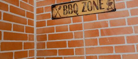 Un mur de briques sur lequel est affiché un panneau indiquant « Zone barbecue ».