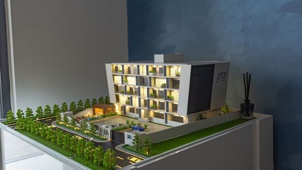 A model of a modern building with multiple floors, a rooftop, and a landscaped area with trees and a pathway. - Luxurious Studio close to USA embassy (Accra)