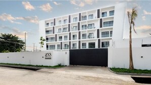 A modern multi-story building with a clean, white facade and a black entrance gate. - Luxurious Studio close to USA embassy (Accra)