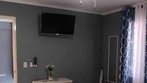A hotel room with a bed, a desk, a television, and a ceiling fan.