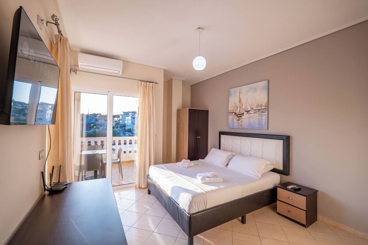 A bedroom with a bed, bedside table, and a view of the outdoors.