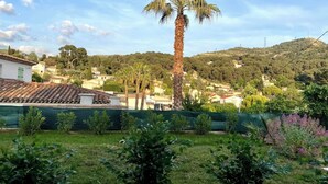 A residential area with a prominent palm tree, houses with tiled roofs, and a hilly backdrop. - Guest House in Allauch (Allauch)