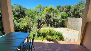 An outdoor patio with a table and chairs, surrounded by greenery and a view of trees and hills. - Guest House in Allauch (Allauch)