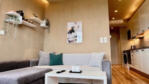A modern living room with a sofa, a coffee table, and a kitchen in the background.