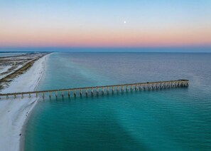 A pier extending into a calm sea with a beach on one side. - 🌊 Sugar Beach | Soundside Access, Resort Perks, 4BR Family-Friendly (Navarre)