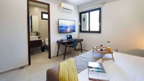 Une chambre d’hôtel avec un lit, un bureau avec un ordinateur portable, une télévision, un plateau de petit-déjeuner et une fenêtre.