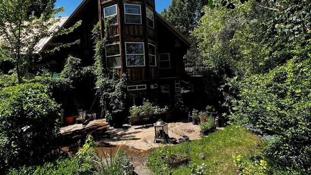 A rustic wooden cabin with multiple windows and a stone staircase leading to the entrance. - Delightful retreat Log Home in Horseshoe Bend, ID (Horseshoe Bend)