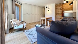 Een moderne woonkamer met een bank, stoel, houten tafel en een kledingkast.