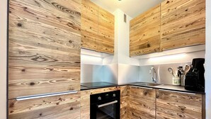 Een kleine keuken met houten kastjes, een zwart aanrecht en een ingebouwde oven.