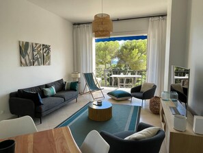 A modern living room with a sofa, chairs, a dining table, and a balcony with a table and chairs.