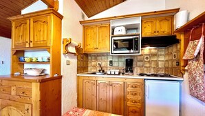 Eine Küche mit Holzausstattung, einer Mikrowelle, einer Kaffeemaschine und einem Kühlschrank.