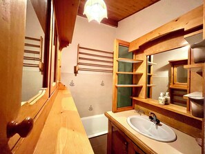 A wooden bathroom with a sink, mirror, and towel rack. - Les Toits des Cateaux (Combloux)