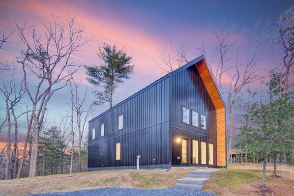 Un bâtiment moderne doté d’un toit en pente, de grandes fenêtres et d’un mur d’accent en bois.