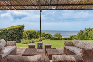 An outdoor seating area with wicker furniture and a view of the sea. - Beachfront Recluse by Cadenzalux (Sintra)