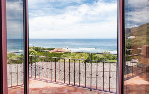 Uma varanda com vista para o oceano e um edifício ao longe.
