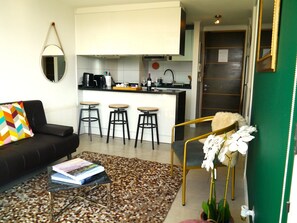 Un salon moderne avec un canapé noir, une table basse et un tapis à motifs.