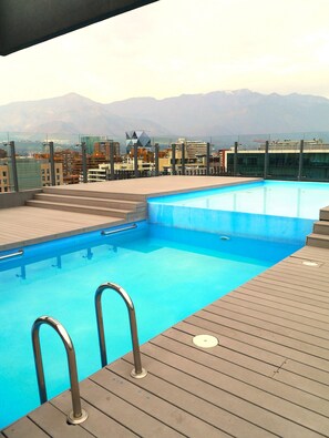 Ein Pool auf dem Dach mit freiem Blick auf die Stadt und die dahinter liegenden Berge.