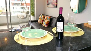 A dining area with a bottle of wine, two glasses, a green plate, and a black table.