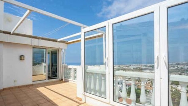 A balcony with a clear view of the sea and cityscape.
