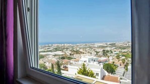 A view from a window overlooking a coastal town with buildings and a clear sky.
