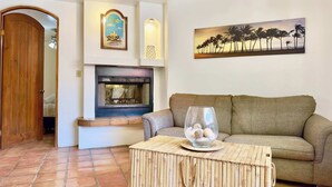A living room with a fireplace, a sofa, a coffee table with decorative items, and a painting on the wall.
