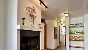 A hallway with a fireplace, shelves with decorative items, and a tiled floor.