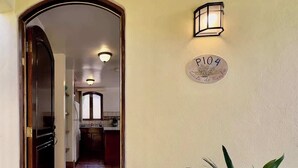 A hallway with a wooden door, a potted plant, a wall-mounted light fixture, and a sign with the number 104.