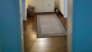 A hallway with a white dresser, a mirror, a lamp, and a rug.