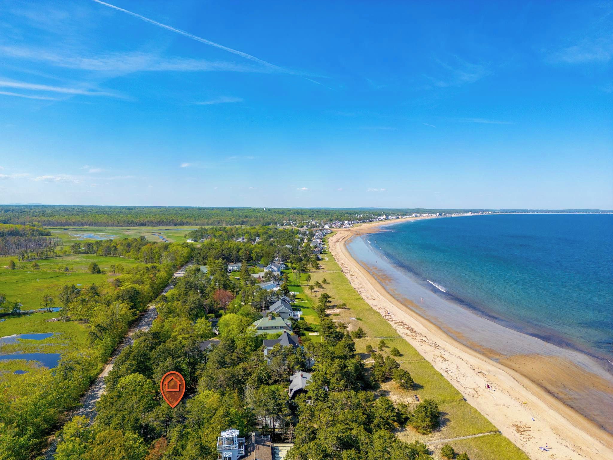 Ein Küstenwohngebiet mit Häusern entlang des Strandes, einem klaren Himmel und einem Fluss, der durch die Landschaft fließt.