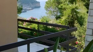 Un balcón con vistas a un paisaje costero, que incluye una masa de agua y montañas a lo lejos.