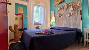 Un dormitorio con una cama, una mesita de noche, una lámpara, un cactus y una ventana con cortinas.