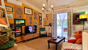 Una sala de estar con televisión, sofá, mesa de centro y una planta en maceta.