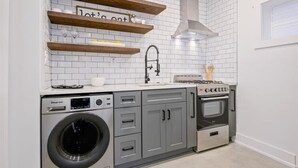 A compact kitchen with a built-in washer and dryer, a gas stove, and a microwave. - 2 Bedroom Loft Style Home in ATL near Downtown (Atlanta)
