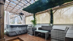 A covered patio area with wicker furniture, a hot tub, and a view of the outdoors. - 2 Bedroom Loft Style Home in ATL near Downtown (Atlanta)
