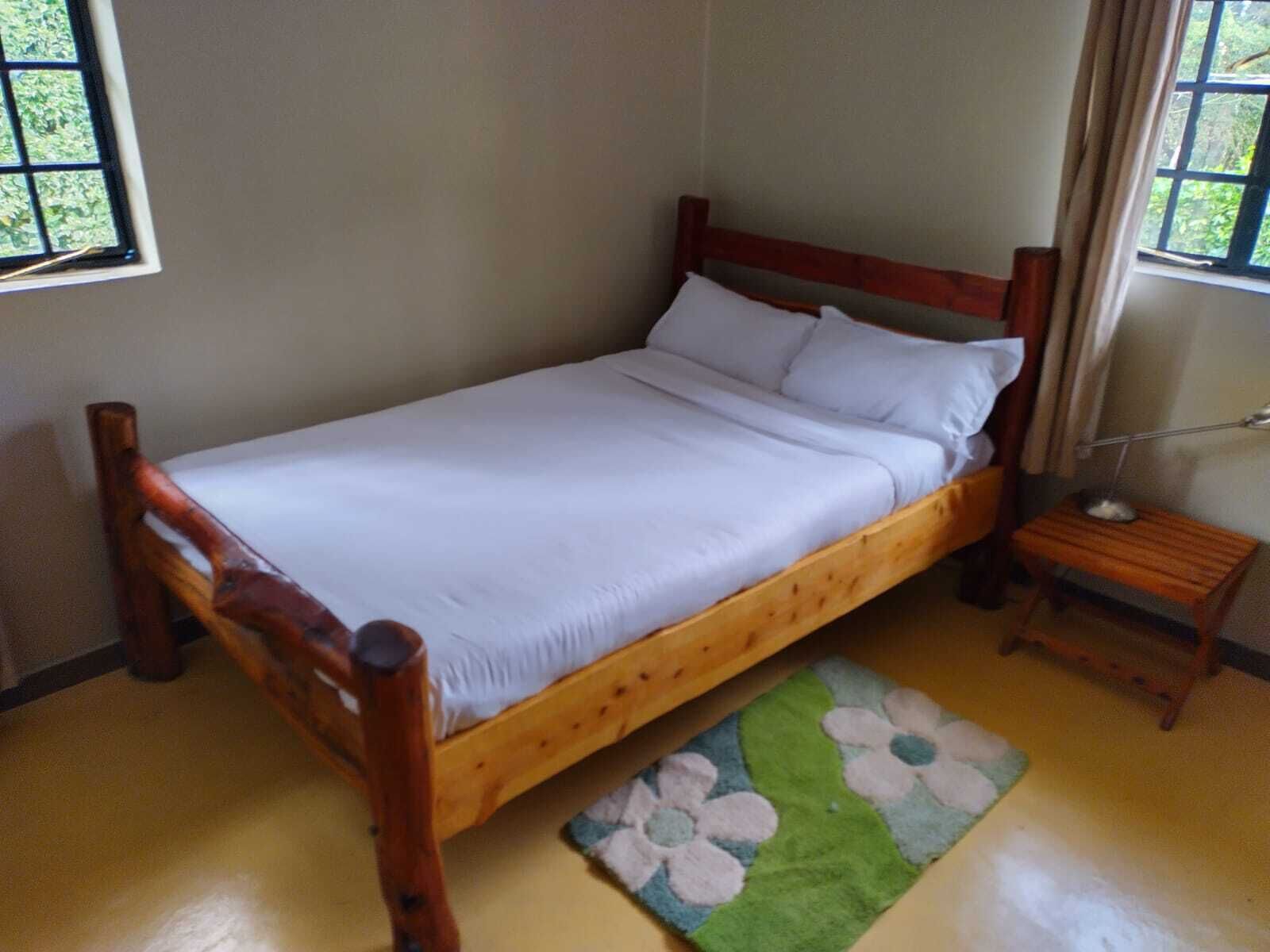 A single bed with a wooden frame and white bedding in a room with a small bedside table and a lamp.