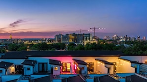 A residential area with multiple houses, some with visible balconies and a prominent building with a pink-lit entrance. - The Dolly Den! • Murals and Glam | Private Rooftop (Nashville)