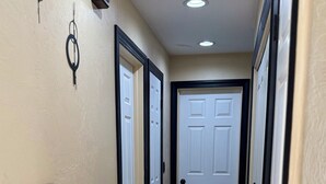 A hallway with two white doors, a light switch, and a ceiling vent.