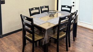 A dining area with a round table, six chairs, and decorative wall art.