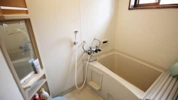 A small bathroom with a bathtub, a shower, a toilet, and a window.