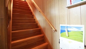 A wooden staircase with a handrail, a calendar, and a picture frame on the wall. - Guest House Aman (Amami)