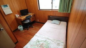 A bedroom with a bed, a desk with a computer, a chair, and a window with curtains. - Guest House Aman (Amami)