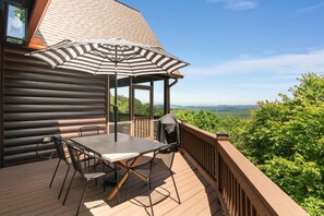 A wooden deck with a table and chairs, an umbrella, and a view of the mountains. - Sunrock Chalet: Discover Modern Luxe Vibes • Hot-Tub • Pool Table • Epic Views (Blue Ridge)