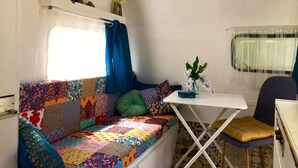Un espace de vie accueillant et compact, avec un canapé coloré à motifs matelassés, une petite table et une chaise.